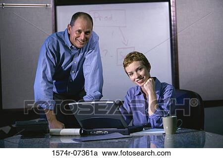 Stock Image - Portrait of a businessman and a businesswoman in front of a laptop. Fotosearch
