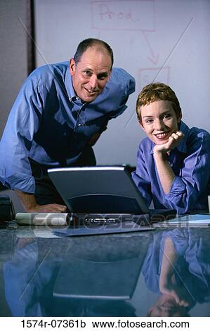 Stock Image - Portrait of a businessman and a businesswoman in front of a laptop. Fotosearch