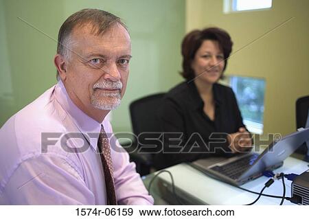 Portrait of a businessman and a businesswoman sitting in an office View Large Photo Image Stock Photo - Portrait of a businessman and a businesswoman sitting in an office. Fotosearch