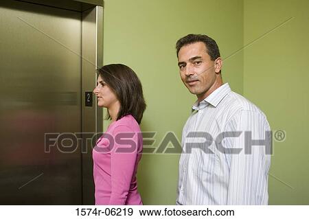 Stock Photo - Portrait of a businessman and a businesswoman standing near an elevator. Fotosearch