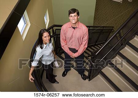 Stock Photo - Portrait of a businessman and a businesswoman standing on stairs. Fotosearch