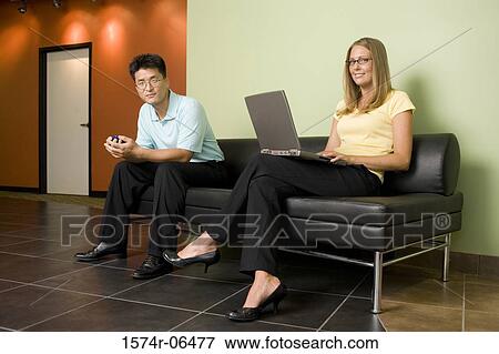 Portrait of a businessman and a businesswoman sitting on a couch in an office View Large Photo Image Stock Photo - Portrait of a businessman and a businesswoman sitting on a couch in an office. Fotosearch