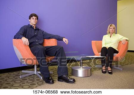 Stock Photo - Portrait of a businessman and a businesswoman sitting in arm chairs in an office. Fotosearch