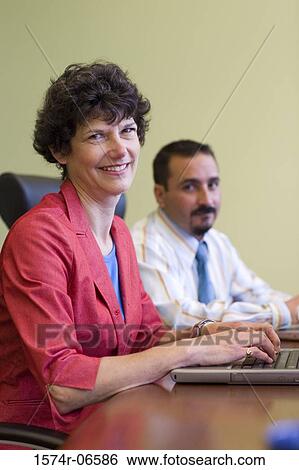 Portrait of a businessman and a businesswoman using a laptop in an office View Large Photo Image Stock Photograph - Portrait of a businessman and a businesswoman using a laptop in an office. Fotosearch