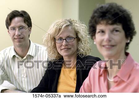 Stock Image - Portrait of a businessman and two businesswomen in an office. Fotosearch