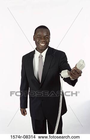 Picture - Portrait of a businessman holding a telephone receiver. Fotosearch