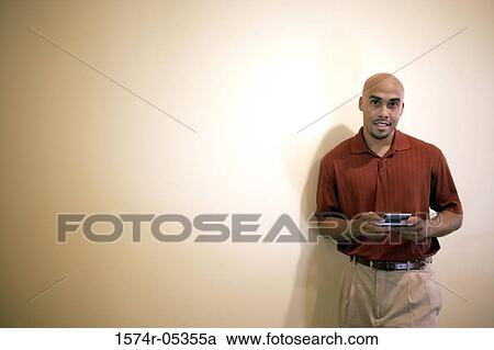 Stock Image - Portrait of a businessman holding a hand held device. Fotosearch