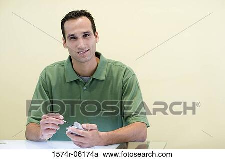 Stock Image - Portrait of a businessman holding a hand held device. Fotosearch