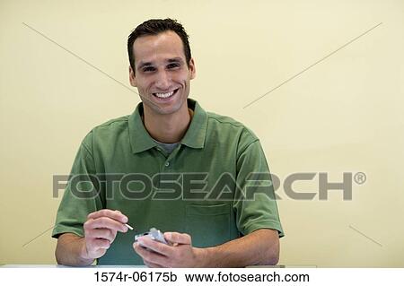 Stock Image - Portrait of a businessman holding a hand held device. Fotosearch