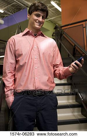 Portrait of a businessman holding a hand held device View Large Photo Image Stock Image - Portrait of a businessman holding a hand held device. Fotosearch