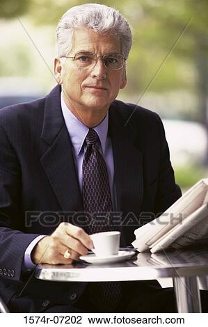 Portrait of a businessman holding a newspaper and a cup of coffee View Large Photo Image Stock Image - Portrait of a businessman holding a newspaper and a cup of coffee. Fotosearch