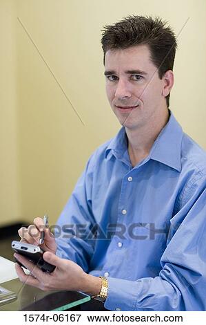 Stock Photo - Portrait of a businessman holding a hand held device. Fotosearch