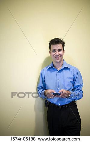 Stock Photo - Portrait of a businessman holding a hand held device. Fotosearch