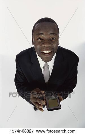 Portrait of a businessman holding a hand held device View Large Photo Image Stock Photo - Portrait of a businessman holding a hand held device. Fotosearch