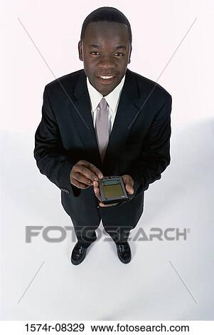 Portrait of a businessman holding a hand held device View Large Photo Image Stock Photo - Portrait of a businessman holding a hand held device. Fotosearch