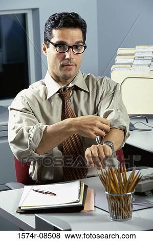 Portrait of a businessman seated at an office desk rolling up his sleeves View Large Photo Image Stock Photo - Portrait of a businessman seated at an office desk rolling up his sleeves. Fotosearch
