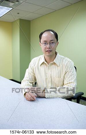 Portrait of a businessman sitting in an office View Large Photo Image Stock Image - Portrait of a businessman sitting in an office. Fotosearch