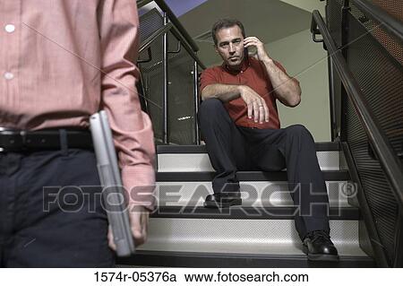 Stock Image - Portrait of a businessman sitting on a staircase talking on a mobile phone. Fotosearch