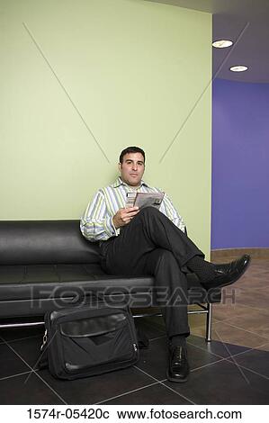 Stock Image - Portrait of a businessman sitting on a couch in an office. Fotosearch