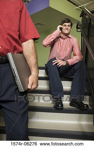 Portrait of a businessman sitting on a staircase talking on a mobile phone View Large Photo Image Stock Photograph - Portrait of a businessman sitting on a staircase talking on a mobile phone. Fotosearch