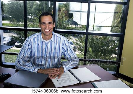 Portrait of a businessman sitting with a laptop in front of him in an office View Large Photo Image Stock Image - Portrait of a businessman sitting with a laptop in front of him in an office. Fotosearch
