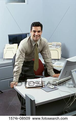 Portrait of a businessman standing behind an office desk View Large Photo Image Stock Photo - Portrait of a businessman standing behind an office desk. Fotosearch