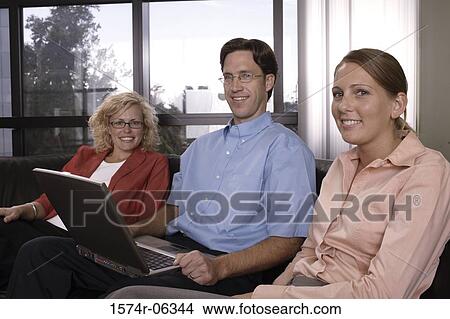 Portrait of a businessman using a laptop with two businesswomen sitting beside him View Large Photo Image Picture - Portrait of a businessman using a laptop with two businesswomen sitting beside him. Fotosearch