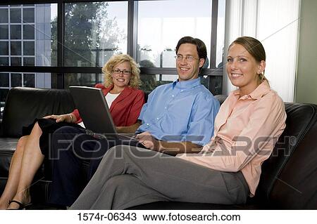 Portrait of a businessman using a laptop with two businesswomen sitting beside him View Large Photo Image Stock Image - Portrait of a businessman using a laptop with two businesswomen sitting beside him. Fotosearch
