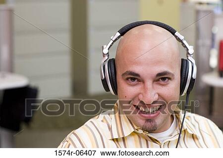 Stock Photo - Portrait of a businessman wearing headphones in an office. Fotosearch