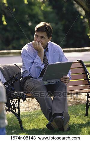 Portrait of a businessman with a laptop sitting on a park bench View Large Photo Image Stock Image - Portrait of a businessman with a laptop sitting on a park bench. Fotosearch