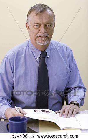 Portrait of a businessman with a magazine in an office View Large Photo Image Stock Photo - Portrait of a businessman with a magazine in an office. Fotosearch