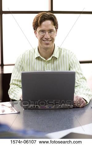 Portrait of a businessman working on a laptop in an office View Large Photo Image Stock Photo - Portrait of a businessman working on a laptop in an office. Fotosearch