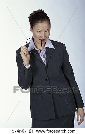 Stock Image - Portrait of a businesswoman biting the shaft of her eyeglasses. Fotosearch