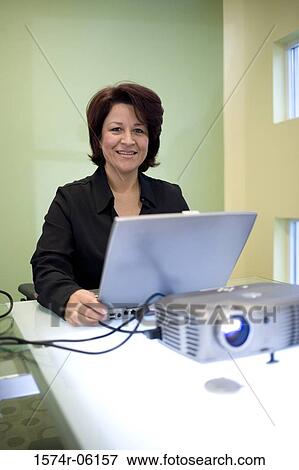 Stock Photo - Portrait of a businesswoman sitting in front of a laptop in an office. Fotosearch