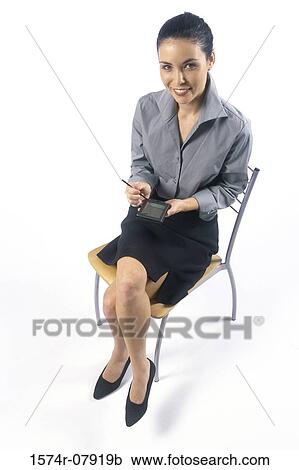 Portrait of a businesswoman sitting on a chair holding a hand held device View Large Photo Image Stock Image - Portrait of a businesswoman sitting on a chair holding a hand held device. Fotosearch