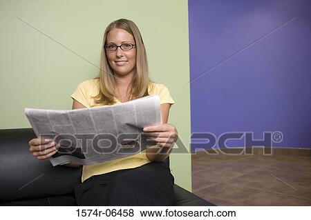 Stock Photo - Portrait of a businesswoman sitting on a couch reading a newspaper in an office. Fotosearch