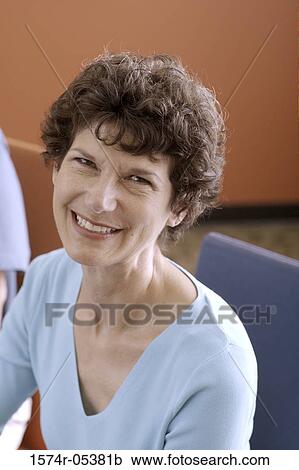 Stock Image - Portrait of a businesswoman smiling in an office. Fotosearch