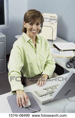 Stock Photo - Portrait of a businesswoman smiling holding a computer mouse. Fotosearch