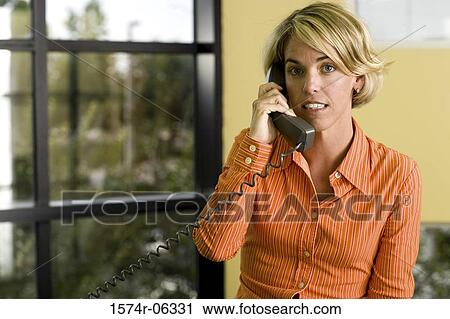 Stock Image - Portrait of a businesswoman talking on a telephone in an office. Fotosearch