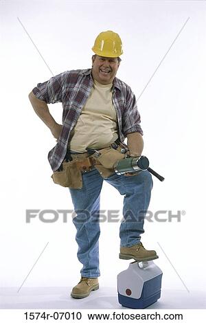 Stock Image - Portrait of a construction worker wearing a hardhat and resting his foot on a ice box. Fotosearch