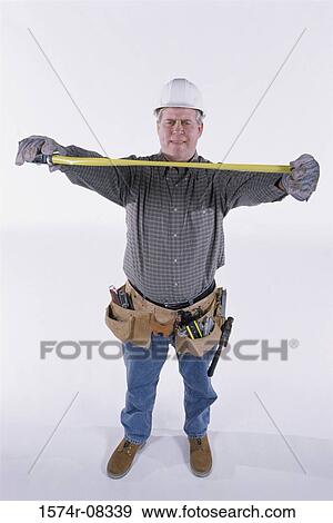 Stock Photo - Portrait of a construction worker holding a measuring tape. Fotosearch