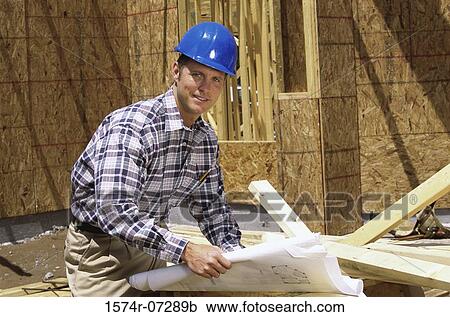Portrait of a foreman standing at a construction site holding blueprints View Large Photo Image Stock Image - Portrait of a foreman standing at a construction site holding blueprints. Fotosearch