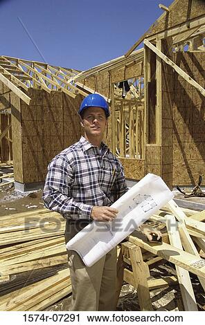 Portrait of a foreman standing at a construction site holding blueprints View Large Photo Image Stock Image - Portrait of a foreman standing at a construction site holding blueprints. Fotosearch