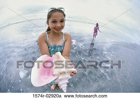 Portrait of a girl holding a conch shell View Large Photo Image Stock Image - Portrait of a girl holding a conch shell. Fotosearch