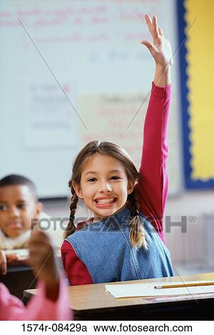 Stock Image - Portrait of a girl raising her hand in class. Fotosearch
