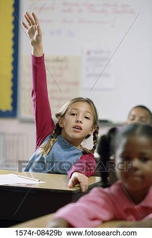 Stock Image - Portrait of a girl raising her hand in class. Fotosearch