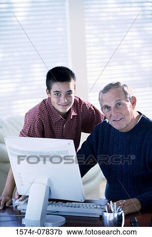 Stock Image - Portrait of a grandfather working on a computer with his grandson. Fotosearch