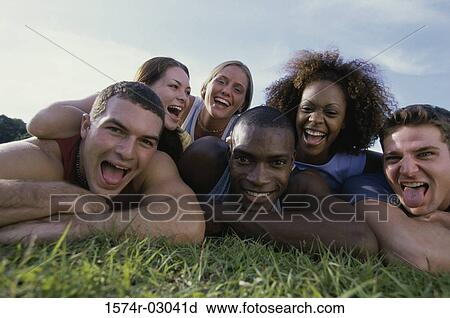 Stock Image - Portrait of a group of young people lying on grass. Fotosearch