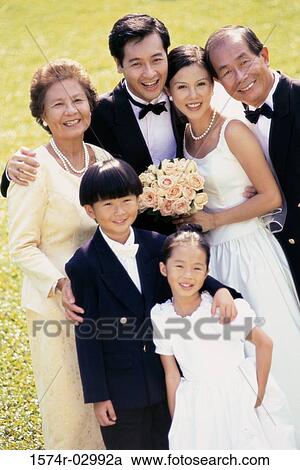 Stock Image - Portrait of a newlywed couple standing with their parents. Fotosearch