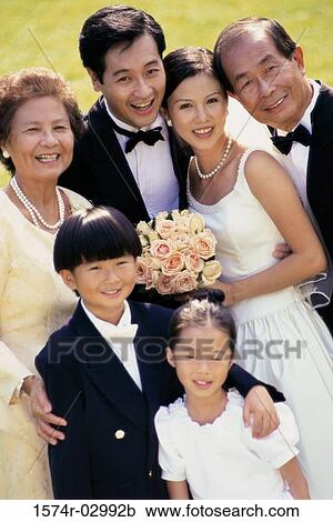 Stock Image - Portrait of a newlywed couple standing with their parents. Fotosearch